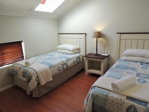 Un dormitorio con dos camas y una mesa con lámpara. en 83 @ The Dunes, en Plettenberg Bay