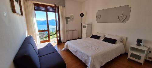 a bedroom with a bed and a couch and a window at APPARTAMENTO BELVEDERE 3 in Stresa