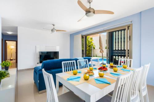 a dining room and living room with a table and a blue couch at TORVISCAS SUNSET VILLA 4 rooms & private Jacuzzi in Adeje