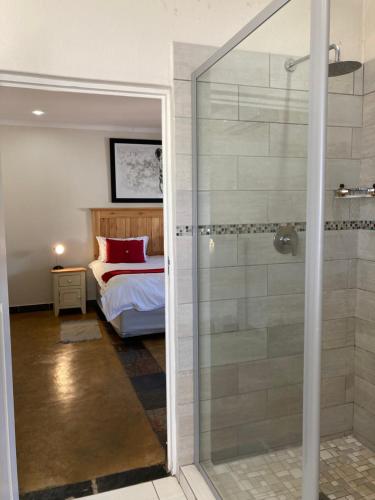 a bathroom with a shower and a bedroom with a bed at Bergdale Cottages in Hazyview