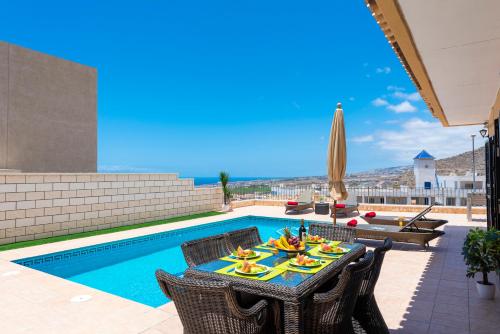 a patio with a table and chairs next to a pool at TORVISCAS SUNSET VILLA 4 rooms & private Jacuzzi in Adeje