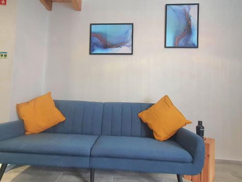 Sofá azul con 2 almohadas naranjas en una habitación en Xagi House - Montargil, en Montargil