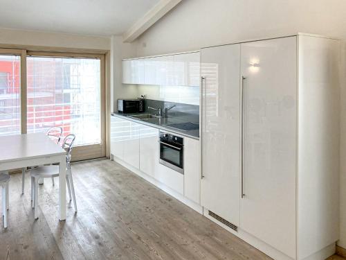 a white kitchen with a table and a refrigerator at Elegante appartamento [Trento centro] Carpe Diem in Trento