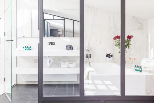 波尔多Villas Foch Boutique Hotel & Spa Bordeaux的一间拥有白色墙壁和大玻璃门的浴室