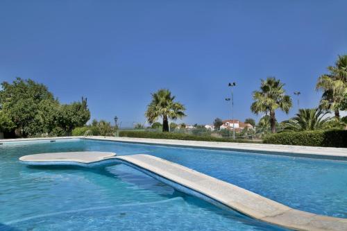 a swimming pool with blue water and palm trees at Turim Club D'Azeitao Hotel in Setúbal