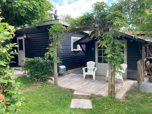a black house with a chair on a patio at Chalet Wild Forest, knus chalet op de Veluwe met gratis parkeren in Putten