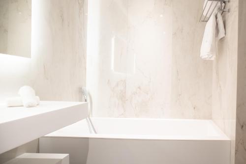 a white bathroom with a tub and a sink at Villas Foch Boutique Hotel & Spa Bordeaux in Bordeaux