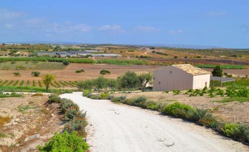 un camino de tierra en un campo con un edificio blanco en Kapuhala Sicily en Marzamemi