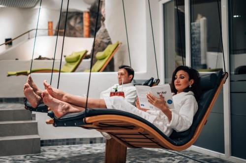 two people sitting in a swinging chair with a laptop at Hotel Wutzschleife in Rötz