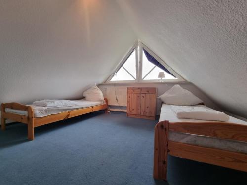 a attic room with two beds and a window at Ferienhaus Baltrumkieker Links in Neßmersiel