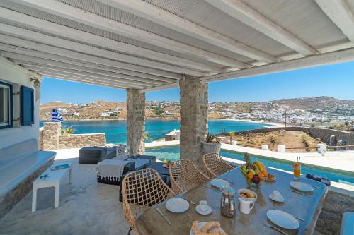 a patio with a table with a view of the water at CORFOS BLUE MYKONOS in Ornos