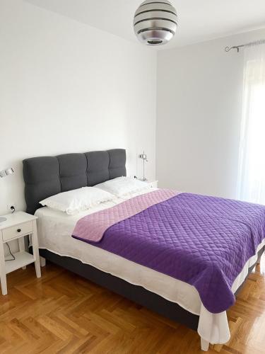 um quarto com uma cama com um cobertor roxo em Apartman Jelena em Trebinje