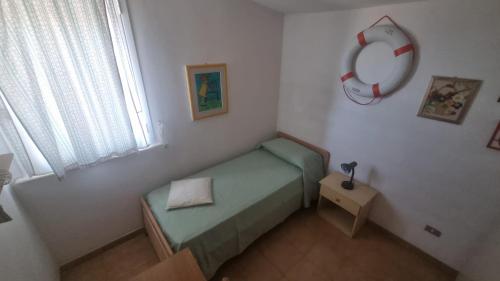 Habitación pequeña con cama y reloj en la pared en Casa Rossella con vista sul mare, en Pachino