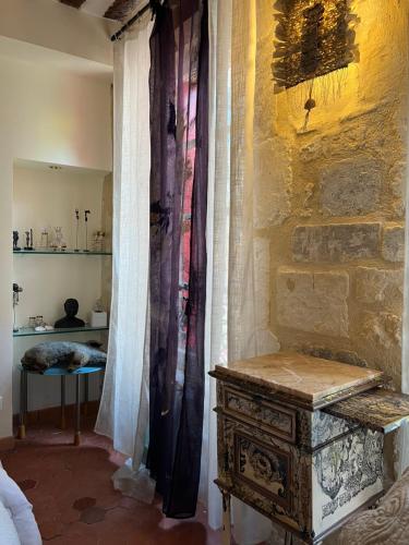 Habitación con pared de piedra, mesa y cortinas. en Le Regardeur en Saint-Rémy-de-Provence