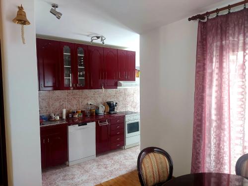 - une cuisine avec des placards rouges et un lave-vaisselle blanc dans l'établissement Dom Kuća, à Kolašin