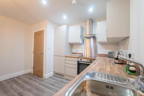 a kitchen with white cabinets and a stainless steel sink at The Queens Arms Apartments in Liverpool