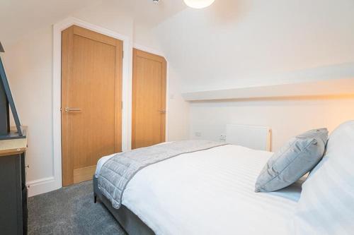 a bedroom with a white bed and a wooden cabinet at The Queens Arms Apartments in Liverpool