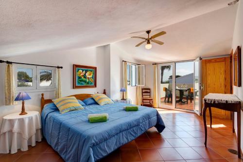 a bedroom with a blue bed and a balcony at Villa Maggie by Villa Plus in Cala en Blanes