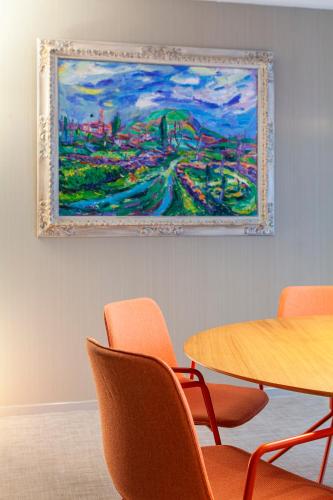 a painting hanging on a wall next to a table and chairs at Hotel Olympia Valencia in Alboraya