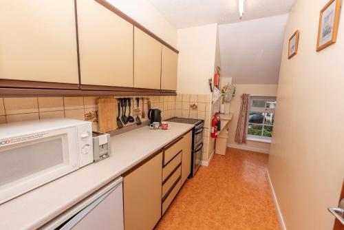 a kitchen with white cabinets and a microwave at Barton House in Woolacombe