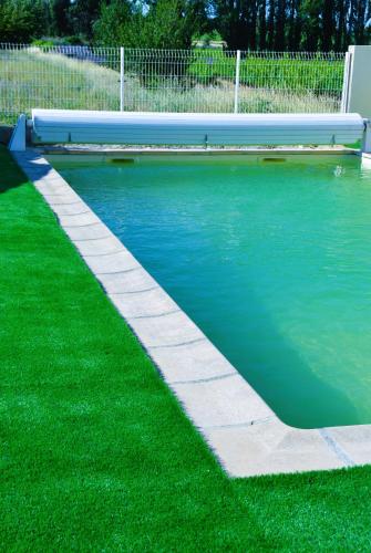 - une piscine avec un banc sur l'herbe dans l'établissement LA PETITE MACHOTTE, à Valréas