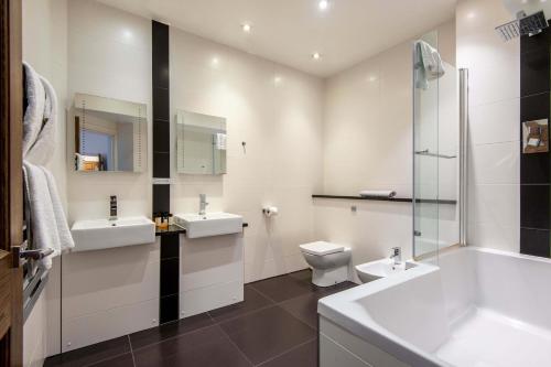 a white bathroom with two sinks and a toilet at Apartment 3, 48 Bishopsgate by City Living London in London