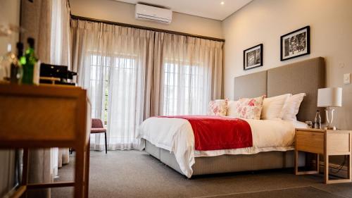 a bedroom with a large bed with a red blanket at Meerendal Boutique Hotel in Durbanville
