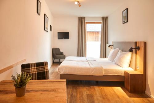 a hotel room with a bed and a chair at Dormio Hotel Obertraun in Obertraun