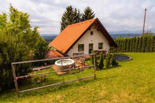 een klein huis met een oranje dak in een tuin bij Panorama Glamping Visole in Slovenska Bistrica