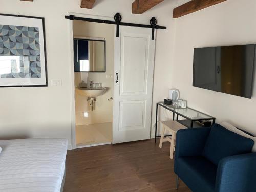 1 dormitorio con 1 cama, 1 silla azul y TV en Old Town Inn en Rijeka
