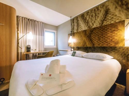 una camera d'albergo con un grande letto bianco con un cartello sopra di ibis Avignon Centre Gare ad Avignone