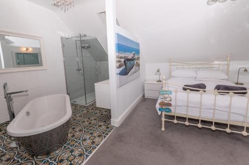 a bathroom with a tub and a bed and a shower at The White Cottage in Woolacombe