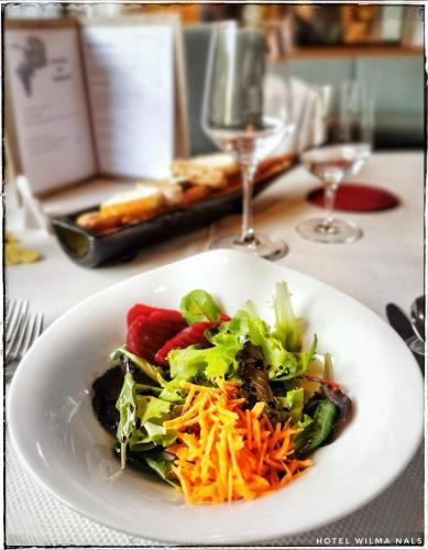 a white plate with a salad on a table at Hotel Wilma in Nalles