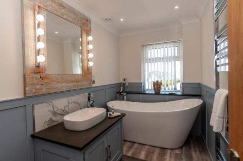 a bathroom with a tub and a sink and a mirror at Coastal Retreat in Woolacombe