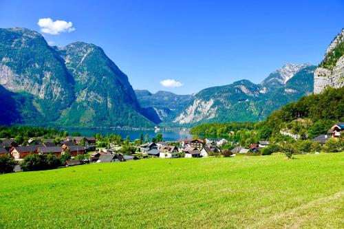a village with a lake and mountains in the background at Dormio Hotel Obertraun in Obertraun