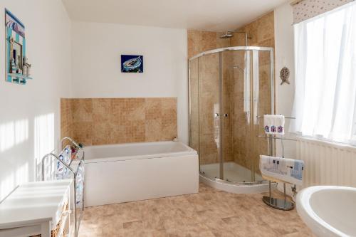 a bathroom with a tub and a shower and a sink at Heatherdale in Mortehoe