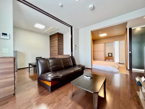 a living room with a leather couch and a bed at Hamamoto Palace Taniyama - Vacation STAY 11965 in Kagoshima