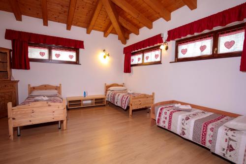 a room with two beds and windows and wooden floors at B&B da mamma Lo in Tolmezzo