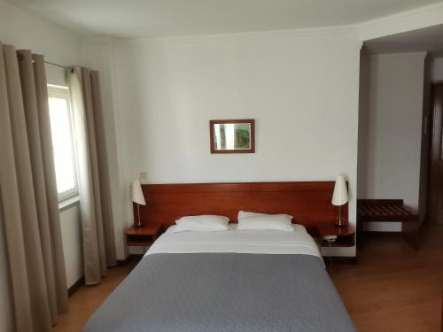 une chambre avec un grand lit avec une tête de lit en bois dans l'établissement Hot Water Guest House, à Termas de São Pedro do Sul