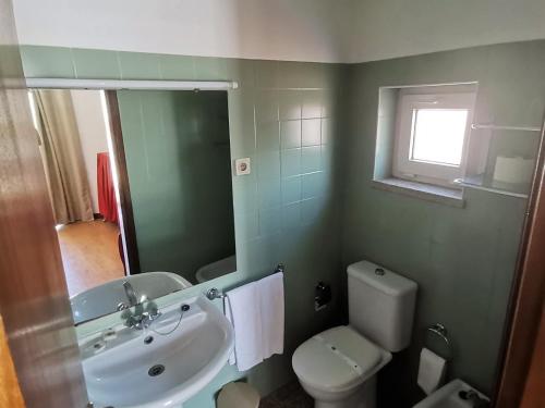 a bathroom with a white toilet and a sink at Hot Water Guest House in Termas de Sao Pedro do Sul