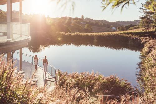 two people standing on a dock next to a lake at Hotel Vier Jahreszeiten Loipersdorf in Loipersdorf bei Fürstenfeld