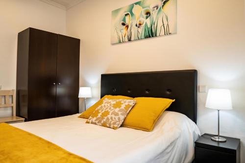 een slaapkamer met een groot bed met gele kussens bij Casa Terraço in Fuzeta