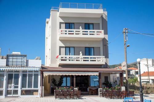a building with tables and chairs in front of it at Argo Rooms-Papadakis in Kissamos
