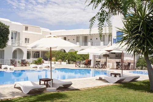 una piscina del complejo con sombrillas, mesas y sillas en Polos Hotel Paros, en Parikia