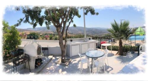 a patio with a tree and a table and chairs at Panoramic Holidays - Deluxe 6 in Peyia