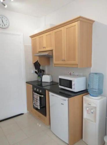 a kitchen with wooden cabinets and a white microwave at Panoramic Holidays - Deluxe 6 in Peyia