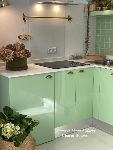 a kitchen with green and white cabinets and flowers at Amarante-Quinta D’Manuel Maria, Rural Charm Houses in Amarante