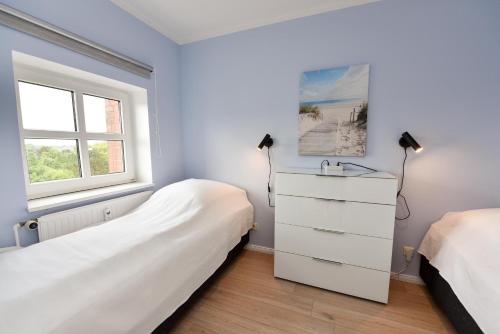 1 Schlafzimmer mit 2 Betten, einer Kommode und einem Fenster in der Unterkunft "Appartementhaus Deichgraf" Appartement D450 in Döse
