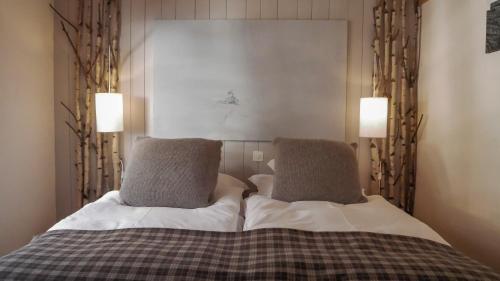 a bedroom with a bed with two pillows at Hôtel Le Grand Chalet Favre in Saint-Luc