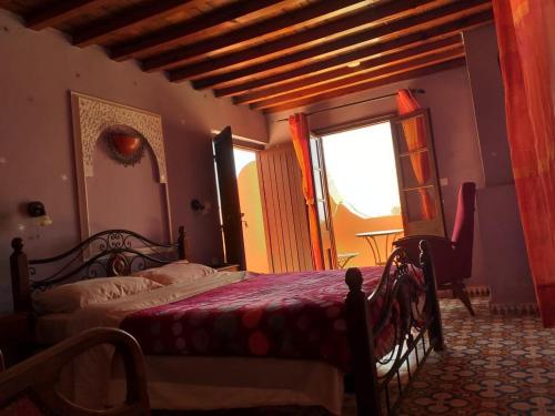 a bedroom with a bed and a large window at Riad Ksar El Jadida Maroc in El Jadida